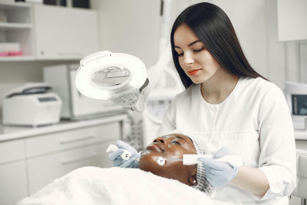 A dermatologist applies skincare treatment to a client in a clinic setting.